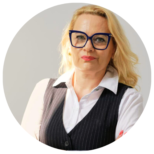 Eliza Borowiak, pedagog wspierający rozwój dzieci i młodzieży w centrum psychologicznym w Warszawie, w eleganckim stroju i okularach, na jasnym tle.