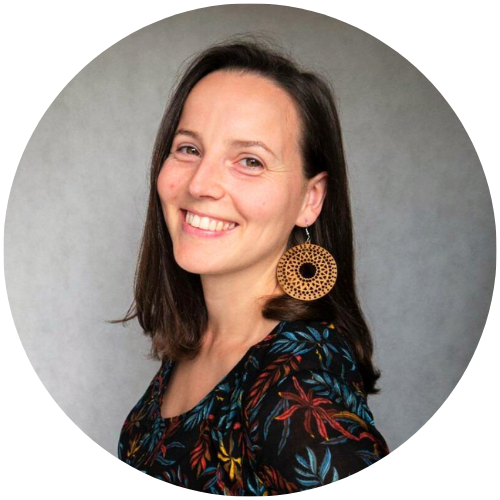 Monika Figat, psycholog z centrum psychologicznego w Warszawie, uśmiechnięta, w ciemnej bluzce i dużych kolczykach, na szarym tle.